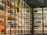 Glass refrigerated display cases filled with rows of yogurt in a grocery store